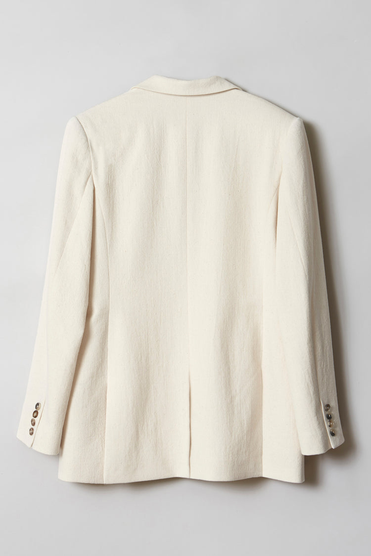 A cream-hued jacket with horn-buttoned sleeves showed flat from the back.