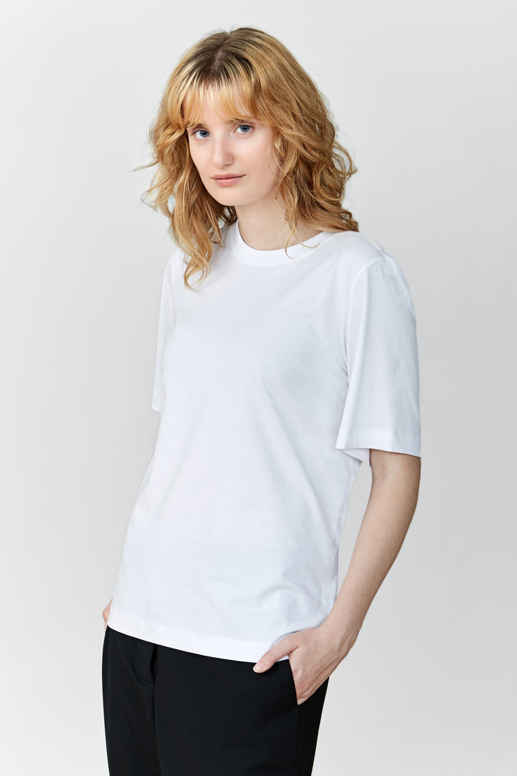 A woman wearing a white regular T-shirt with a classic crewneck and black trousers.