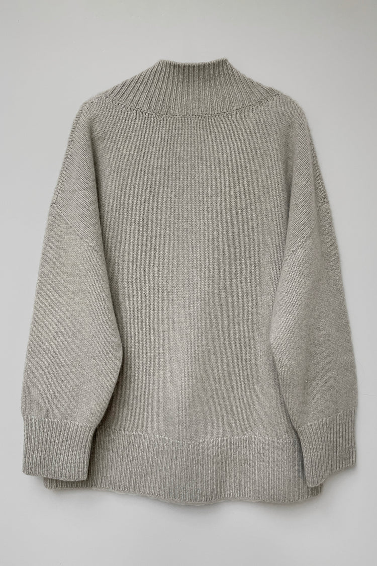 Back of a cosy v-neck cashmere sweater in light grey photographed flat.