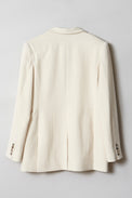 A cream-hued jacket with horn-buttoned sleeves showed flat from the back.